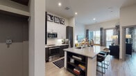Located in McKinney, TX, this single-floor residence offers a thoughtfully designed open-concept layout with contemporary finishes throughout. The kitchen is a standout feature, showcasing dark cabinetry contrasted by crisp white upper cabinets, a herringbone tile backsplash, and a full suite of stainless steel appliances including a French door refrigerator, electric range with microwave, and dishwasher. A generous granite-topped island with an undermount sink and built-in shelving serves as both a functional workspace and a casual dining area with bar seating. Light wood-look flooring flows seamlessly throughout the home, enhancing its modern aesthetic. The living area benefits from large windows that invite natural light and offer outdoor views, creating an airy, welcoming atmosphere. The bedroom is a comfortable retreat, featuring oversized windows, wall-mounted lighting, and direct access to a well-organized walk-in closet with built-in shelving. The bathroom continues the refined design with granite countertops, dark wood cabinetry, a large vanity mirror, and a tiled soaking tub with a shower. High ceilings throughout the space amplify the sense of openness, while recessed lighting provides a clean, polished look. This residence combines functional design with modern style in a well-appointed McKinney location.