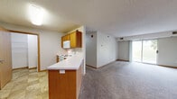 Located at 925 41st St NW in Rochester, Minnesota, this 2-bedroom, 1-bathroom residence offers a practical and well-organized single-floor layout. The open-concept kitchen and living area form the heart of the home, with the kitchen featuring warm oak cabinetry, white appliances including a refrigerator, electric range with microwave, and a peninsula with a white countertop that provides additional workspace and a natural divide between the two areas. Tile flooring runs throughout the kitchen, while plush carpet extends across the living room, which is brightened by a sliding glass door leading to a private patio and offering views of a green outdoor area. Both bedrooms are carpeted and receive natural light through windows overlooking the surrounding grounds. The primary bedroom includes access to a generously sized walk-in closet outfitted with wire shelving on multiple walls, providing ample storage. The full bathroom is finished with tile flooring, an oak vanity with a white countertop, a large mirror, and a lighted vanity fixture. A dedicated laundry area accommodates a stacked washer and dryer unit alongside additional wire shelving. Textured ceilings and warm wood-toned trim are consistent throughout, giving the space a cohesive, functional character.
