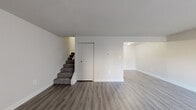 Located at 1235 Beaumont Ave in Baltimore, MD, this two-story, 2-bedroom, 1-bathroom home offers a practical and well-organized layout spread evenly across two floors. The main level features an open living area with durable wood-look vinyl flooring in a neutral gray tone, crisp white walls, and a carpeted staircase leading to the upper level. A closet with bifold doors provides convenient storage on the main floor. The galley-style kitchen is outfitted with rich dark cabinetry, light-toned countertops, and black appliances including a gas range and refrigerator, with a single-basin sink positioned beneath overhead storage. Upstairs, a hallway connects the two bedrooms and the full bathroom. Both bedrooms feature plush carpeting, natural light from double-hung windows with blinds, and individual closets — the primary bedroom includes a generous closet with a full-width rod and shelf. The shared full bathroom is finished in white, featuring a tub and shower combination with tiled surround and a handheld showerhead. The home's clean, neutral palette throughout creates a bright and move-in ready atmosphere.