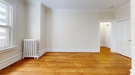 Located at 149 MacLaren Street in Ottawa's centrally situated Centretown neighbourhood, this 2-bedroom, 1-bathroom unit offers a blend of classic architectural character and functional layout across a single floor. Warm-toned hardwood flooring runs throughout the living areas and bedrooms, complemented by elegant crown moulding and crisp white baseboards that reflect the building's traditional design heritage. Cast-iron radiators are present in multiple rooms, serving as both a functional heating source and a charming period detail. The entrance features a distinctive panelled door with decorative diamond-pane sidelights and transom window, allowing natural light to filter into the space. The primary bedroom is generously proportioned and benefits from a large window overlooking the surrounding neighbourhood. The second bedroom provides additional flexibility as a guest room or home office. A corridor connects the rooms, leading to the kitchen and the full bathroom. The bathroom is finished with white tile wainscoting, a soaking tub, a pedestal sink, and a bright window that introduces natural light. The neutral, light palette of warm whites across all walls creates a clean and cohesive ambiance throughout the unit.
