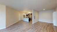 This single-floor residence offers a thoughtfully designed open-concept layout that seamlessly connects the living area and kitchen. Light-toned wood plank flooring runs throughout the main living spaces, complementing the neutral warm-beige walls and crisp white trim to create a bright, clean aesthetic. Large floor-to-ceiling windows in the living area invite an abundance of natural light, enhancing the sense of spaciousness.

The kitchen is a standout feature, centered around a generous white-topped island with an undermount sink and pendant lighting above. Dark espresso cabinetry provides a striking contrast against the light countertops, while a full suite of stainless steel appliances — including a refrigerator, range, and microwave — adds a polished, modern touch. A tile backsplash and track lighting complete the culinary space.

The bedrooms are carpeted for comfort and each includes a dedicated closet with built-in shelving. One bedroom benefits from a window with exterior views, adding natural light to the room.

Two bathrooms serve the residence, each featuring dark vanity cabinetry, white countertops, and wood-look flooring. One bathroom includes a shower, while the other offers a full tub-shower combination. Hallway closets provide additional storage throughout the unit.