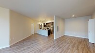 This single-floor residence offers a thoughtfully designed open-concept layout that seamlessly connects the living area and kitchen. Light-toned wood plank flooring runs throughout the main living spaces, complementing the neutral warm-beige walls and crisp white trim to create a bright, clean aesthetic. Large floor-to-ceiling windows in the living area invite an abundance of natural light, enhancing the sense of spaciousness.

The kitchen is a standout feature, centered around a generous white-topped island with an undermount sink and pendant lighting above. Dark espresso cabinetry provides a striking contrast against the light countertops, while a full suite of stainless steel appliances — including a refrigerator, range, and microwave — adds a polished, modern touch. A tile backsplash and track lighting complete the culinary space.

The bedrooms are carpeted for comfort and each includes a dedicated closet with built-in shelving. One bedroom benefits from a window with exterior views, adding natural light to the room.

Two bathrooms serve the residence, each featuring dark vanity cabinetry, white countertops, and wood-look flooring. One bathroom includes a shower, while the other offers a full tub-shower combination. Hallway closets provide additional storage throughout the unit.