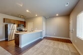 Located at 2309 SW Plaza Pkwy in Ankeny, Iowa, this one-bedroom, one-bathroom residence offers a thoughtfully designed single-floor layout that maximizes functionality and comfort. The open-concept living, dining, and kitchen area serves as the heart of the home, where warm-toned luxury vinyl plank flooring flows through the kitchen and transitions into plush carpeting in the living space. The kitchen is well-appointed with warm wood cabinetry, light quartz countertops, a peninsula with an integrated sink, and a full suite of stainless steel appliances including a refrigerator, electric range, and over-the-range microwave. Recessed lighting and a dedicated track light fixture illuminate the space effectively. The living area benefits from natural light through multiple windows with views of the surrounding neighborhood. The bedroom is a comfortable, carpeted retreat with a ceiling fan, a window for natural light, and access to two closets for ample storage. The bathroom features wood-tone cabinetry with a quartz vanity top, a full tub-shower combo with brushed nickel fixtures, and durable wood-look flooring. A dedicated laundry area and utility room round out this efficient and move-in-ready residence.