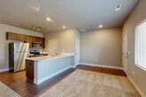 Located at 2309 SW Plaza Pkwy in Ankeny, Iowa, this one-bedroom, one-bathroom residence offers a thoughtfully designed single-floor layout that maximizes functionality and comfort. The open-concept living, dining, and kitchen area serves as the heart of the home, where warm-toned luxury vinyl plank flooring flows through the kitchen and transitions into plush carpeting in the living space. The kitchen is well-appointed with warm wood cabinetry, light quartz countertops, a peninsula with an integrated sink, and a full suite of stainless steel appliances including a refrigerator, electric range, and over-the-range microwave. Recessed lighting and a dedicated track light fixture illuminate the space effectively. The living area benefits from natural light through multiple windows with views of the surrounding neighborhood. The bedroom is a comfortable, carpeted retreat with a ceiling fan, a window for natural light, and access to two closets for ample storage. The bathroom features wood-tone cabinetry with a quartz vanity top, a full tub-shower combo with brushed nickel fixtures, and durable wood-look flooring. A dedicated laundry area and utility room round out this efficient and move-in-ready residence.