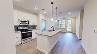 Located at 510 McLean St in Belmont, NC, this well-designed 2-bedroom, 2-bathroom unit offers a thoughtfully planned single-level layout with modern finishes throughout. Light-toned hardwood-style flooring flows continuously across the space, creating a cohesive and clean aesthetic.

The open-concept kitchen and living area serves as the heart of the unit. The kitchen features white shaker cabinetry extending to the ceiling, stainless steel appliances including a French door refrigerator, electric range, and built-in microwave, complemented by a dark tile backsplash and quartz-style countertops. A central island with an undermount sink and matte black faucet provides additional prep space and is accented by pendant lighting overhead. Natural light enters through windows at the far end of the living area, which also includes balcony access.

The primary bedroom includes a dedicated walk-in closet and an en suite bathroom featuring a single-sink vanity with quartz countertop, matte black hardware, and a glass-enclosed shower. The second bedroom offers a ceiling fan and a window with natural light. The second bathroom includes a tub-shower combination and matching vanity finishes. A dedicated laundry room with full-size washer and dryer completes the unit.