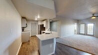 This single-floor residence offers a thoughtfully designed layout that balances functionality and comfort. The entry leads into an open-concept living and kitchen area, where rich hardwood-style flooring flows seamlessly underfoot. The kitchen is a standout, featuring a central island with a quartz countertop and undermount sink, white cabinetry, stainless steel appliances including a refrigerator and dishwasher, and recessed lighting overhead. The kitchen opens directly to a spacious living area finished with plush carpeting, creating a warm and inviting atmosphere.

The bedrooms are generously sized, each finished with soft carpeting and equipped with ceiling fans for year-round comfort. Natural light enters through large windows fitted with blinds, offering views of surrounding greenery. Closet space is well-integrated throughout.

The bathrooms are clean and modern in design. One features a full tub-shower combination with white tile surround and a curved curtain rod, while the other offers a vessel sink atop a quartz vanity with ample cabinet storage, wood-look flooring, and a well-lit mirror. Throughout the home, neutral gray tones on the walls create a cohesive, move-in-ready aesthetic that is both timeless and versatile.