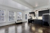 Located in the heart of downtown Los Angeles, this single-floor loft-style unit at 400 S Main Street blends industrial character with modern updates. Polished concrete floors run throughout the entire space, lending a raw, urban aesthetic that is both durable and visually striking. The open-concept layout is bright and airy, with multiple large windows fitted with blinds along the exterior walls, inviting generous natural light and offering views of the surrounding streetscape.

The kitchen is a standout feature, outfitted with dark charcoal cabinetry extending from floor to ceiling, white quartz countertops, and a geometric patterned tile backsplash. Stainless steel and black appliances — including a gas range, refrigerator, and dishwasher — complete the contemporary cooking space. Exposed conduit and structural elements along the ceiling reinforce the loft's industrial character.

The bathroom is clean and well-appointed, featuring subway tile surrounding a full soaking tub and shower, polished concrete flooring, a wall-mounted vanity, and warm brass ceiling fixture accents. A classic interior door with a transom glass panel adds a nod to the building's architectural heritage. The unit's open living area provides flexible space suitable for a variety of configurations, making it a functional and distinctive downtown residence.