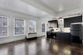 Located in the heart of downtown Los Angeles, this single-floor loft-style unit at 400 S Main Street blends industrial character with modern updates. Polished concrete floors run throughout the entire space, lending a raw, urban aesthetic that is both durable and visually striking. The open-concept layout is bright and airy, with multiple large windows fitted with blinds along the exterior walls, inviting generous natural light and offering views of the surrounding streetscape.

The kitchen is a standout feature, outfitted with dark charcoal cabinetry extending from floor to ceiling, white quartz countertops, and a geometric patterned tile backsplash. Stainless steel and black appliances — including a gas range, refrigerator, and dishwasher — complete the contemporary cooking space. Exposed conduit and structural elements along the ceiling reinforce the loft's industrial character.

The bathroom is clean and well-appointed, featuring subway tile surrounding a full soaking tub and shower, polished concrete flooring, a wall-mounted vanity, and warm brass ceiling fixture accents. A classic interior door with a transom glass panel adds a nod to the building's architectural heritage. The unit's open living area provides flexible space suitable for a variety of configurations, making it a functional and distinctive downtown residence.