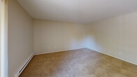 This single-floor, 2-bedroom, 2-bathroom unit at 650 SW 201st Ave in Aloha, Oregon offers a practical and well-organized layout. The living room is comfortably proportioned, featuring neutral carpet, baseboard heating, and a sliding glass door fitted with vertical blinds that opens onto a private wooden balcony, allowing natural light to fill the space.

The kitchen is positioned adjacent to the living area and features white cabinetry extending to the ceiling, a peninsula with a warm-toned laminate countertop, a coil-burner electric cooktop, and a full-size refrigerator. Stone-look tile flooring throughout the kitchen adds durability and contrast to the neutral palette.

Both bedrooms are carpeted and finished with warm beige walls. Each room includes a sliding-panel closet and baseboard heating, with windows providing natural light. The primary bedroom offers a generous footprint with ample wall space.

The two bathrooms mirror each other in finish, each featuring tile flooring, white vanity cabinetry, warm-toned laminate countertops, and a wide mirror above the sink. The overall aesthetic throughout the unit is clean, neutral, and functional.