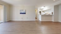 This single-floor residence offers a clean, neutral aesthetic throughout, with a thoughtful layout designed for comfortable everyday living. The open-concept living area features warm wood-look vinyl plank flooring and crown molding, flowing seamlessly into a bright kitchen equipped with white cabinetry, white appliances, light countertops, and a convenient pass-through breakfast bar. The bedrooms are carpeted and generously sized, each benefiting from natural light through large windows fitted with blinds. At least one bedroom includes a dedicated walk-in closet with built-in wire shelving and hanging rods, providing ample storage. The space includes two full bathrooms, each outfitted with a tub-shower combination, a vanity with white cabinetry, and wood-look vinyl flooring. Louvered closet doors and consistent white trim and baseboards throughout contribute to a cohesive, polished interior. The neutral color palette of soft whites and warm beiges creates a calm, versatile ambiance that adapts easily to a variety of furnishing styles. Overall, the space is well-maintained and move-in ready, offering a practical and comfortable living environment.