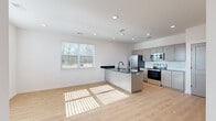 This thoughtfully designed single-story unit in Fort Smith, Arkansas offers a clean, modern aesthetic with an efficient open-concept layout. The living and kitchen areas share a bright, unified space anchored by light hardwood-style flooring and recessed lighting overhead. A central kitchen island with a dark countertop and undermount sink serves as the focal point, complemented by gray shaker-style cabinetry with gold hardware, a white subway tile backsplash, and a full suite of stainless steel appliances including a French door refrigerator, electric range, built-in microwave, and dishwasher. Natural light filters in through a large window, enhancing the open feel of the main living area.

The bedroom features plush carpet flooring, a ceiling fan with light fixture, and a generously sized window that provides natural light and outdoor views. An adjacent walk-in closet offers multi-level hanging rods and shelving, maximizing storage capacity. The bathroom includes a full tub-shower combo with crisp white surrounds, matte black fixtures, a toilet, and the same hardwood-style flooring found throughout the main living areas. The overall ambiance is clean, contemporary, and move-in ready.
