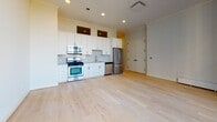 Located at 170 S 6th St in Philadelphia's Old City neighborhood, this single-floor residence combines classic architectural details with contemporary finishes throughout. Light-toned hardwood flooring runs continuously across the unit, creating a cohesive and airy feel from room to room.

The open living area is anchored by large, multi-pane windows that allow abundant natural light to fill the space while framing views of the surrounding urban streetscape. Crown molding adds a refined architectural touch to the bright, neutral-toned walls.

The kitchen is outfitted with white shaker-style cabinetry extending to the ceiling, light stone countertops, a subway tile backsplash, and a full suite of stainless steel appliances including a gas range, built-in microwave, dishwasher, and French door refrigerator. Recessed lighting enhances the clean, functional layout.

The bedroom features frosted glass sliding closet doors and crown molding, maintaining the unit's consistent design language. A hallway connects the rooms efficiently, with louvered and glass-paneled interior doors adding thoughtful detail throughout.

The bathroom includes a soaking tub with an overhead shower, enclosed by a glass panel, and finished with large-format white tile for a clean, contemporary aesthetic.