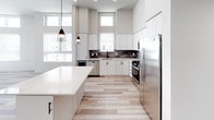 Located at 1921 Union St in Anaheim, California, this contemporary single-floor residence showcases a clean, modern design with a cohesive neutral palette and high-quality finishes throughout. The open-concept kitchen is a standout feature, offering white flat-front cabinetry extending to the ceiling, a textured gray tile backsplash, quartz countertops, a large center island, stainless steel appliances including a gas range and French door refrigerator, and stylish pendant lighting. Light wood-look flooring flows seamlessly from the kitchen into the spacious living area, which benefits from abundant natural light through oversized windows and clerestory panes, along with a ceiling fan for added comfort. The bedrooms are carpeted, bright, and airy, each equipped with ceiling fans and large windows dressed with white blinds. The bathrooms maintain the modern aesthetic with light wood-grain vanities, dual sinks, matte black fixtures, quartz countertops, and large mirrors. One bathroom features a soaking tub and shower combination with clean white tile surround. Throughout the residence, matte black hardware provides a striking contrast against the predominantly white and light-toned surfaces, creating a sophisticated and cohesive contemporary atmosphere.