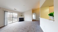 Located at 12913 Falling Water Cir in Germantown, MD, this two-bedroom, two-bathroom residence offers a thoughtfully arranged single-floor layout designed for comfortable everyday living. The open living room serves as the heart of the home, featuring a corner fireplace with a white mantel, soft wall-to-wall carpeting, and vaulted ceilings that enhance the sense of openness. A sliding glass door provides direct access to a private balcony with outdoor views, while a pass-through window connects the living area to the kitchen, maintaining a bright, connected feel. The galley-style kitchen is equipped with light wood cabinetry, white countertops, a coil electric range, black refrigerator, and durable luxury vinyl plank flooring, providing ample storage and functionality. Both bedrooms are carpeted and finished in neutral tones, with large windows that allow generous natural light and outdoor views. The primary bedroom includes a double-door closet for added storage. The two bathrooms each feature a tub-shower combination, wood-toned vanity cabinetry, and vinyl plank flooring. A hallway connects the private areas of the home, completing a practical and cohesive floor plan.