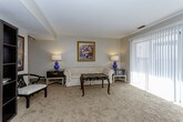 This single-floor residence offers a thoughtfully organized layout that balances comfort and functionality throughout. The open living area is carpeted and generously proportioned, bathed in natural light streaming through large windows with vertical blinds, and accented by a ceiling fan. It flows seamlessly into a dedicated dining space, creating an ideal environment for both relaxing and entertaining.

The kitchen is well-equipped with dark cabinetry, granite-style countertops, a white tile backsplash, and a full suite of stainless steel appliances including a gas range, over-the-range microwave, and a full-size refrigerator. Light tile flooring completes the clean, functional aesthetic.

The residence includes two carpeted bedrooms, each offering a calm, neutral palette. The primary bedroom features a walk-in closet and direct access to an en-suite bathroom, while a wall sconce adds a warm ambient glow. The second bedroom is equally comfortable, with a bright window and convenient closet access.

Two bathrooms serve the home: the en-suite includes a shower-tub combination with a sliding glass door, and the second bathroom features a vanity with dark cabinetry and tile flooring. Both are finished with neutral tones for a clean, cohesive look throughout the home.