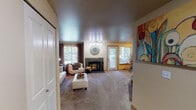 Located at 1296 NE Mount Olympus Lane in Bremerton, Washington, this single-floor residence offers a well-organized and comfortable layout ideal for everyday living. The spacious living room serves as the heart of the home, anchored by a tile-surround fireplace and bathed in natural light through large windows dressed with rich curtain panels. A sliding glass door and an additional exterior door provide direct access to the outdoors, enhancing the sense of openness. The galley-style kitchen is thoughtfully designed with light maple cabinetry, ample counter space, a stainless steel sink, and a full suite of appliances including a range, microwave, and dishwasher, all set on easy-care tile flooring. The unit features two bedrooms, both carpeted and filled with natural light from recessed window bays. The primary bedroom is generously proportioned, while the secondary bedroom offers a quiet nook suitable as a sitting or flex room. Two full bathrooms serve the unit, each with a shower-tub combination and tile flooring. One bathroom includes a vanity with light maple cabinetry and overhead lighting. In-unit laundry is also present, adding everyday convenience. Throughout, warm neutral tones and textured ceilings create a welcoming and cohesive atmosphere.