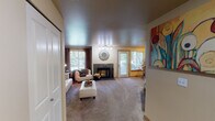 Located at 1296 NE Mount Olympus Lane in Bremerton, Washington, this single-floor residence offers a well-organized and comfortable layout ideal for everyday living. The spacious living room serves as the heart of the home, anchored by a tile-surround fireplace and bathed in natural light through large windows dressed with rich curtain panels. A sliding glass door and an additional exterior door provide direct access to the outdoors, enhancing the sense of openness. The galley-style kitchen is thoughtfully designed with light maple cabinetry, ample counter space, a stainless steel sink, and a full suite of appliances including a range, microwave, and dishwasher, all set on easy-care tile flooring. The unit features two bedrooms, both carpeted and filled with natural light from recessed window bays. The primary bedroom is generously proportioned, while the secondary bedroom offers a quiet nook suitable as a sitting or flex room. Two full bathrooms serve the unit, each with a shower-tub combination and tile flooring. One bathroom includes a vanity with light maple cabinetry and overhead lighting. In-unit laundry is also present, adding everyday convenience. Throughout, warm neutral tones and textured ceilings create a welcoming and cohesive atmosphere.