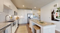 This well-appointed single-story residence offers 1 bedroom and 2 bathrooms within a thoughtfully designed floor plan. The open-concept kitchen and living area serves as the heart of the home, featuring crisp white cabinetry, a geometric patterned tile backsplash, stainless steel appliances — including a French door refrigerator, range, and microwave — and a granite-topped peninsula with built-in seating, ideal for casual dining or entertaining. Wood-style plank flooring runs consistently throughout the entire unit, lending a cohesive, modern aesthetic.

The living area is bright and welcoming, benefiting from multiple windows that invite natural light and outdoor views. A light-toned hallway with recessed lighting connects the main living spaces to the private areas of the home. The bedroom is a comfortably sized retreat, equipped with a ceiling fan, dual windows, and direct access to a walk-in closet outfitted with dual hanging rods and shelving. One bathroom features a soaking tub with tile surround, while both bathrooms are finished with granite vanity countertops and white cabinetry. Clean white walls, panel-style doors, and recessed lighting throughout complete the contemporary, move-in-ready interior.