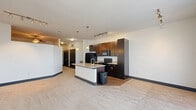 Located at 881 Third Ave SW in Carmel, Indiana, this one-bedroom, one-bathroom residence offers a thoughtfully designed single-floor layout that maximizes both function and style. The open-concept living area seamlessly connects the kitchen, dining, and living spaces, creating a bright and airy atmosphere. The kitchen is a standout feature, showcasing rich dark cabinetry that reaches toward the ceiling, black appliances, track lighting, and a central island with a light granite countertop and pendant lighting overhead — ideal for meal prep and casual dining. The living room is carpeted and bathed in natural light through large windows and a sliding glass door, and is finished with a ceiling fan for added comfort. A distinctive barn-style sliding door adds a modern-industrial accent to the hallway, which leads to three closets and an in-unit laundry area. The bedroom offers a cozy, well-proportioned retreat with a dedicated closet featuring built-in shelving and a hanging rod. The bathroom is clean and contemporary, appointed with large-format tile flooring, a dark-framed vanity with a white countertop, a soaking tub with tile surround, and brushed nickel fixtures throughout. This well-appointed residence combines practical storage solutions with a cohesive, modern design aesthetic.