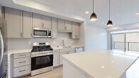Located at 309 Second St in Farmington, MN, this thoughtfully designed 2-bedroom, 1-bathroom unit offers a clean, modern aesthetic across a single floor. The standout kitchen is a highlight, featuring grey shaker-style cabinetry with matte black hardware, a subway tile backsplash, white quartz countertops, and a large center island. A full suite of stainless steel appliances — including a gas range, built-in microwave, refrigerator, and dishwasher — completes the space. Light wood-style flooring flows through the kitchen and living areas, complemented by recessed lighting and gold pendant fixtures. The living room opens directly to a private balcony through a sliding glass door, filling the space with natural light and offering outdoor views. The primary bedroom features plush carpeting and a large window that brings in additional daylight. The second bedroom is carpeted as well, providing a comfortable, quiet retreat. The full bathroom is finished with white cabinetry, quartz counters, matte black fixtures, a large vanity mirror, and a combination tub and shower. Throughout the unit, the neutral color palette and modern finishes create a cohesive, contemporary living environment.