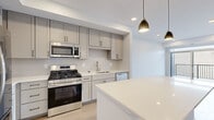 Located at 309 Second St in Farmington, MN, this thoughtfully designed 2-bedroom, 1-bathroom unit offers a clean, modern aesthetic across a single floor. The standout kitchen is a highlight, featuring grey shaker-style cabinetry with matte black hardware, a subway tile backsplash, white quartz countertops, and a large center island. A full suite of stainless steel appliances — including a gas range, built-in microwave, refrigerator, and dishwasher — completes the space. Light wood-style flooring flows through the kitchen and living areas, complemented by recessed lighting and gold pendant fixtures. The living room opens directly to a private balcony through a sliding glass door, filling the space with natural light and offering outdoor views. The primary bedroom features plush carpeting and a large window that brings in additional daylight. The second bedroom is carpeted as well, providing a comfortable, quiet retreat. The full bathroom is finished with white cabinetry, quartz counters, matte black fixtures, a large vanity mirror, and a combination tub and shower. Throughout the unit, the neutral color palette and modern finishes create a cohesive, contemporary living environment.