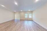 Located at 6 Truman Circle in Rochester, NH, this three-bedroom, three-bathroom home spans three floors, offering a generous and well-organized layout. The exterior presents a clean, neutral vinyl-sided facade with a covered entryway and landscaped surroundings. The main level hosts a combined kitchen and living room, where light hardwood-style flooring flows throughout. The kitchen is equipped with warm honey-toned cabinetry, granite countertops, and stainless steel appliances, including a refrigerator and dishwasher. The adjacent living area features recessed lighting, vertical blinds, and windows that invite natural light and views of the surrounding greenery. The bathrooms are finished with tile flooring, wood vanities topped with granite countertops, and clean, neutral wall tones. The bedrooms are carpeted and bright, with the spacious primary bedroom offering a comfortable private retreat. Hallways connect each level efficiently via a central staircase. The unfinished basement provides substantial utility space with exposed concrete walls and insulated ceilings, ideal for storage or future development. An attached garage adds everyday convenience. Throughout the home, a consistent palette of warm beige walls and white trim creates a cohesive, welcoming atmosphere.