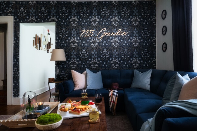 Una elegante zona de estar con mullidos cojines, iluminación cálida y un elegante letrero con la inscripción "715 Grandin". - 715 Grandin Rd