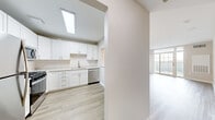 This well-appointed one-bedroom, one-bathroom unit at 5801 Nicholson Lane in Rockville, Maryland offers a thoughtfully designed layout across a single floor. Light-toned luxury vinyl plank flooring flows throughout the main living areas, creating a clean, cohesive aesthetic, while the bedroom is finished with plush carpeting for added comfort.

The open-concept living room is bright and airy, anchored by large sliding glass doors that lead to a private balcony overlooking the outdoors, filling the space with natural light. A pendant chandelier adds a refined touch to the living and dining area.

The kitchen is equipped with white shaker-style cabinetry, a herringbone tile backsplash, light stone countertops, and a full suite of stainless steel appliances including a refrigerator, gas range, microwave, and dishwasher. A skylight above enhances the kitchen's brightness.

The generously sized bedroom features a wide window with outdoor views and direct access to the bathroom. The bathroom is finished with a white vanity with stone countertop, a tiled shower-tub combination, and wood-look flooring. A dedicated hallway closet with built-in shelving and rod provides ample storage, completing this functional and modern Rockville residence.