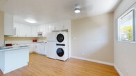 Located at 3903 Conrad Dr in Spring Valley, California, this single-floor home offers three bedrooms and two bathrooms within a thoughtfully laid-out floor plan. Light hardwood-style flooring flows consistently throughout the main living areas and bedrooms, creating a warm, cohesive aesthetic.

The open-concept kitchen and living room area serves as the heart of the home. The kitchen features crisp white cabinetry, a white quartz-style countertop, a peninsula with additional seating space, and white appliances including a range and dishwasher. A stacked in-unit washer and dryer is conveniently integrated into the kitchen area. Large windows and a glass front door flood the living area with natural light and frame views of surrounding greenery.

The primary bedroom is generously sized and includes a mirrored sliding-door closet that adds depth and reflects natural light. Additional bedrooms offer windows with outdoor views, textured ceilings, and ample wall space. A dedicated walk-in closet with built-in shelving provides added storage. The bathrooms include a clean, neutral-toned walk-in shower. A hallway connects the private sleeping quarters to the main living spaces, maintaining a clear and functional layout throughout.