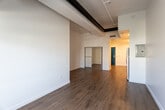 Located in the Koreatown neighborhood of Los Angeles, this single-floor loft-style unit at 3550 W 6th St blends industrial character with modern finishes. The open living area immediately impresses with its soaring ceilings, exposed ductwork, and track lighting rail, evoking a true loft aesthetic. Wide-plank hardwood flooring runs throughout, adding warmth and continuity across the space. Natural light filters in through a large window, brightening the expansive white walls and creating an airy, open atmosphere well-suited for both living and working.

The kitchen is thoughtfully designed with a clean, contemporary sensibility. White flat-panel cabinetry extends to the ceiling, maximizing storage, while a white quartz countertop and subway tile backsplash provide a crisp, polished look. Stainless steel appliances — including a refrigerator, range, over-the-range microwave, and dishwasher — complete the functional setup. A dedicated laundry area with in-unit washer and dryer hookups is conveniently tucked adjacent to the kitchen. The overall layout is efficient yet open, offering flexibility in how the space can be arranged and utilized.