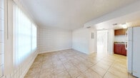 Located at 12401 North 15th Street in Tampa, Florida, this one-bedroom, one-bathroom unit offers a practical and efficiently designed single-floor layout. Light-toned ceramic tile flooring runs throughout the entire space, lending a clean and cohesive look to every room.

The main living area is bright and open, characterized by a distinctive grid-patterned tiled accent wall that adds a unique architectural detail. Natural light filters in through the windows, enhancing the airy feel of the space. A textured ceiling is present throughout.

The kitchen is well-equipped and functional, featuring warm, rich wood cabinetry that extends to the ceiling for ample storage. Stone-look countertops, a gas range, and a full-size refrigerator round out the kitchen's offerings, making it a practical space for everyday cooking.

The bedroom is a comfortable size, complete with a sliding-door closet offering dedicated storage space. Its layout allows for easy furnishing and connects conveniently to the rest of the unit via a hallway.

The bathroom is clean and simply appointed, with a full-size soaking tub and shower combination, a toilet, and a vanity with a mirror — all finished in a bright white palette that maximizes the sense of space. The hallway connects all rooms efficiently, completing this straightforward and functional floor plan.
