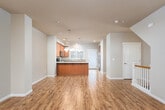 Located at 4507 Briggs Dr SE in Olympia, Washington, this three-floor home offers a thoughtfully designed layout spread across multiple levels. The main living area showcases warm hardwood-style flooring that extends throughout the open-concept space, connecting the living room to the kitchen seamlessly. A white-railed staircase serves as a functional architectural detail, anchoring the main floor's layout.

The kitchen is a standout feature, equipped with warm-toned wooden cabinetry, stainless steel appliances including an electric range, over-the-range microwave, and refrigerator. Light countertops complement the mosaic tile backsplash, while pendant lighting and recessed fixtures illuminate the space. A kitchen island provides additional workspace and casual seating.

A dedicated dining area benefits from natural light through large windows and features an elegant chandelier overhead. Bathrooms include tile flooring, wooden vanities with light stone countertops, and well-lit mirrors. A compact half bath with tile flooring provides added convenience.

The carpeted bedrooms are found on the upper floors, offering comfortable, quiet retreats with natural light from slatted windows. The lower level provides additional carpeted space, suitable for flexible use. Neutral wall tones throughout create a cohesive, welcoming ambiance across all three floors.