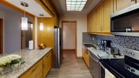Located on the iconic Nicollet Mall in the heart of Minneapolis, this single-floor residence offers a thoughtfully designed layout with a variety of functional spaces. The open living area is highlighted by rich hardwood flooring, warm wood baseboards, and a floor-to-ceiling sliding glass door that frames sweeping city skyline views and opens to a private balcony. A large mirror wall amplifies the sense of space and reflects natural light throughout the main living area, which also features a convenient breakfast bar connecting to the kitchen. The galley-style kitchen is well-equipped with warm wood cabinetry, granite countertops, a mosaic tile backsplash, stainless steel appliances, and a luminous ceiling panel that brightens the workspace. Additional rooms include carpeted bedrooms, one of which also enjoys direct balcony access and city views. The bathrooms are clean and functional—one features a full tub-shower combination with white tile surround, while the other offers a granite vanity counter, pendant lighting, and a separate water closet. Throughout, textured ceilings and neutral tones create a cohesive, understated aesthetic suited to urban living in a prime downtown Minneapolis location.