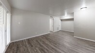 Located at 3523 Fawn Valley Dr in Dallas, Texas, this one-bedroom, one-bathroom unit offers a well-organized single-floor layout comprising a living room, bedroom, kitchen, bathroom, closet, and hallway. Throughout the unit, wood-look laminate flooring in a warm gray tone provides a cohesive and modern aesthetic, complemented by neutral gray walls and white trim.

The living room is a generously proportioned space featuring a textured ceiling, a flush-mount light fixture, and a set of French doors that invite natural light and provide outdoor access. A separate entry door adds functionality to the layout.

The galley-style kitchen is efficiently designed with white shaker-style cabinetry, light stone-patterned countertops, a stainless steel sink, and black appliances including a refrigerator and electric range — maximizing storage and workspace within a compact footprint.

The bedroom is a comfortable, well-sized room with wood-look flooring, a window fitted with horizontal blinds, and an exposed brick accent wall that adds a distinctive architectural character. A dedicated closet is conveniently accessible from the bedroom.

The bathroom features white tile surrounding a full tub-shower combination, a toilet, and a vanity with a light stone countertop, all set on clean white tile flooring. The overall design is straightforward, functional, and move-in ready.
