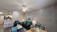 This well-designed single-floor residence offers a cohesive and vibrant interior characterized by recurring grey faux-brick accent walls that lend an urban, contemporary feel throughout. The open-plan living and dining area serves as the heart of the home, featuring wood-look flooring, a ceiling fan with integrated lighting, adjustable track lighting, and a large window dressed with sheer curtains that invites natural light. The living space accommodates comfortable seating alongside a dining area, creating a seamless flow ideal for everyday living and entertaining.

The galley-style kitchen is efficiently laid out with white cabinetry offering generous storage, light countertops, stainless steel appliances including a refrigerator, range, dishwasher, and built-in microwave, as well as an in-unit washer and dryer accessible from the kitchen corridor.

Each bedroom continues the signature brick accent wall design, complemented by carpet flooring, ceiling fans, and windows with roman shades. The rooms each include closet space and areas suitable for a desk or workspace setup. The bathrooms are clean and functional, each featuring a tub-shower combination, wood-look flooring, white vanities with ample counter space, and textured ceilings — providing a practical and comfortable finish throughout.