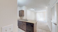 This 490 square foot apartment, situated in Austin's Domain district, maximizes space efficiency in a single-floor layout. The unit features two bathrooms, adding convenience and luxury to the compact living space. The modern kitchen is well-appointed with dark wood cabinetry, stainless steel appliances, and a practical layout that includes ample counter space and a breakfast bar, ideal for casual dining or additional food preparation area.

The main living area showcases an open-concept design, with plush carpeting that adds warmth and comfort. Large vertical blinds cover a sliding glass door, likely leading to a small balcony or patio, allowing for natural light control and outdoor access. The room's neutral color palette and minimalist design create a sense of spaciousness.

One of the bathrooms displays a contemporary design with a shower-tub combination, adorned with a decorative tile border that adds visual interest. The vanity provides storage space, complementing the overall modern aesthetic.

Throughout the apartment, tile flooring in the kitchen and bathroom areas contrasts with the carpeted living spaces, offering both practicality and style. The unit's layout is designed to maximize functionality in a limited square footage, making it an ideal choice for urban dwellers seeking a balance of comfort and convenience in the heart of Austin.