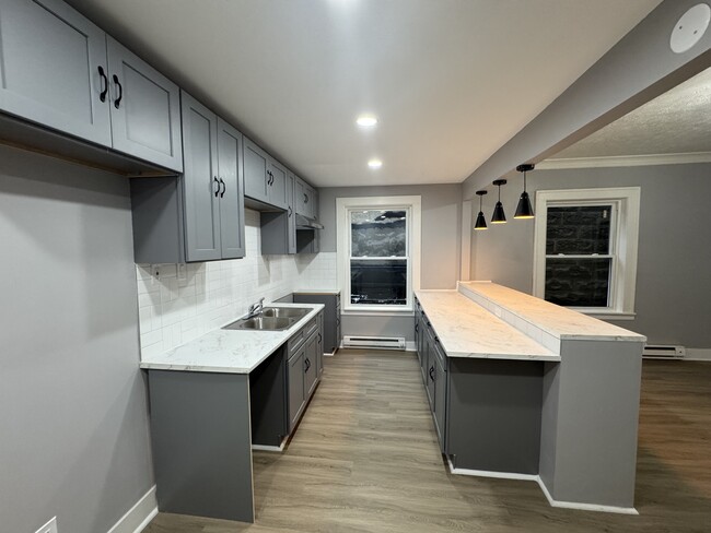 Stylish gray cabinetry, marble-look counters, and updated lighting. - 898-902 Portland Ave