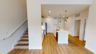 Located along SH 114 in Trophy Club, Texas, this two-story residence offers a clean, contemporary design with a bright, neutral palette carried consistently throughout both levels. Warm-toned wood-look flooring runs seamlessly across the main living areas, complementing the crisp white walls and trim.

The heart of the main level is an open-concept kitchen, designed for both function and style. White shaker cabinetry extends to the ceiling, providing generous storage, while a large center island with a white quartz countertop and undermount sink serves as the focal point. Brushed gold pendant lights hang above the island, adding a refined accent. Stainless steel appliances, including a refrigerator, range, and built-in microwave, are paired with a mosaic tile backsplash. A built-in mudroom nook is conveniently located nearby. Staircase access to the upper level is positioned adjacent to the kitchen area.

The upper floor features generously sized rooms with natural light from multiple windows offering outdoor views. One room showcases notably tall ceilings, enhancing the sense of openness. A full bathroom with a soaking tub and tiled surround serves the upper level, while a well-appointed bathroom with dual white vanities, ample cabinetry, and a large framed mirror is also present. The overall ambiance is modern, clean, and move-in ready.