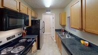 Located at 9158 Fox Lake Dr in Knoxville, Tennessee, this single-floor residence offers a well-organized and comfortable layout designed for everyday living. The galley-style kitchen is equipped with dark granite countertops, light wood cabinetry, black appliances including a range, microwave, and refrigerator, and a double stainless steel sink — all set against tile flooring. Adjacent to the kitchen, a dedicated dining area features a warm chandelier overhead and provides an inviting space for meals. The living room is bright and open, anchored by a ceiling fan with light fixture and offering direct access to an outdoor deck through glass doors, bringing in natural light and outdoor views. Soft carpeting flows throughout the living and sleeping areas, contributing to a cozy atmosphere. The primary bedroom is generously sized with windows allowing natural light and features a textured ceiling. A second bedroom serves well as a home office, complete with windows and ample wall space. Two bathrooms serve the residence — one with a granite-topped vanity and shower, and another with a tub-shower combination. A connecting hallway ties the private and communal spaces together cohesively, completing this practical and comfortable Knoxville home.
