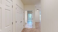 Located on Dutch Meadows Lane in Schenectady, NY, this single-floor residence offers a well-designed, open layout filled with natural light and clean, neutral finishes. The kitchen serves as a central hub of the home, featuring dark espresso cabinetry, granite countertops, stainless steel appliances including a refrigerator, range, and microwave, and a large peninsula with pendant lighting overhead. Light hardwood-style flooring runs through the kitchen, transitioning to plush wall-to-wall carpeting in the living and bedroom areas. The bedrooms are generously proportioned, with large windows that frame views of surrounding greenery, providing a bright and peaceful atmosphere. The primary bedroom includes access to a spacious walk-in closet outfitted with wire shelving along multiple walls for ample storage. The bathroom is appointed with a clean white vanity, white countertop, framed mirror, and tile-style flooring. A dedicated laundry room houses a full-size washer and dryer along with overhead wire shelving, adding everyday convenience. The hallway features a double-door closet, and the overall layout flows efficiently throughout. Crisp white trim, panel-style doors, and a consistently light color palette give the entire space a fresh, move-in-ready feel.
