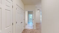 Located on Dutch Meadows Lane in Schenectady, NY, this single-floor residence offers a well-designed, open layout filled with natural light and clean, neutral finishes. The kitchen serves as a central hub of the home, featuring dark espresso cabinetry, granite countertops, stainless steel appliances including a refrigerator, range, and microwave, and a large peninsula with pendant lighting overhead. Light hardwood-style flooring runs through the kitchen, transitioning to plush wall-to-wall carpeting in the living and bedroom areas. The bedrooms are generously proportioned, with large windows that frame views of surrounding greenery, providing a bright and peaceful atmosphere. The primary bedroom includes access to a spacious walk-in closet outfitted with wire shelving along multiple walls for ample storage. The bathroom is appointed with a clean white vanity, white countertop, framed mirror, and tile-style flooring. A dedicated laundry room houses a full-size washer and dryer along with overhead wire shelving, adding everyday convenience. The hallway features a double-door closet, and the overall layout flows efficiently throughout. Crisp white trim, panel-style doors, and a consistently light color palette give the entire space a fresh, move-in-ready feel.