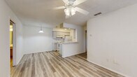 Located at 12012 Holbrook Dr in Hudson, FL, this single-story 2-bedroom, 2-bathroom home offers a practical and well-organized layout. The open-concept living, dining, and kitchen area forms the heart of the home, featuring light luxury vinyl plank flooring throughout, a textured ceiling, and a ceiling fan with integrated lighting. A pendant light fixture accentuates the transition between the living space and the kitchen, which is designed in a galley style with gray cabinetry, light countertops, a white appliance suite including an electric range and refrigerator, and convenient access to a dedicated pantry. The primary bedroom is a comfortable, well-lit space with multiple windows dressed in blinds that allow for ample natural light, complemented by its own ceiling fan and closet. The second bedroom also features LVP flooring, a window, and closet access. Both bathrooms are finished in a clean, bright style with LVP flooring, white fixtures, and vanities with light countertops; one bathroom includes accessibility grab bars around the tub and toilet area. Additional highlights include three closets, a laundry area, and a hallway connecting the private quarters. The overall ambiance is clean, bright, and move-in ready.