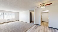 Located at 1900 S Missouri Ave in Casper, Wyoming, this single-floor unit offers three bedrooms and one bathroom within a practical, well-organized layout. The open living area features a combination of plush carpeting and wood-style vinyl flooring, with a ceiling fan providing comfort and light. A large window allows natural light to fill the space, complemented by baseboard heating throughout. The galley-style kitchen is lined with warm wood cabinetry on both sides, offering generous storage and counter space, and is equipped with a range, refrigerator, and stainless steel sink. The flooring transitions seamlessly to wood-style vinyl in this area. Each of the three bedrooms is carpeted and equipped with a ceiling fan. The spacious primary bedroom includes a closet, while the secondary bedrooms also feature individual closets with sliding or bi-fold wood doors. The full bathroom includes a tiled shower-tub combination, a wood-toned vanity, and wood-style vinyl flooring. A hallway connects the rooms efficiently, and an additional closet provides extra storage. Textured ceilings and dark wood trim accents are consistent throughout, giving the unit a cohesive, classic residential aesthetic.