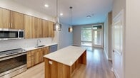 Located at 400 W Swedesford Rd in Berwyn, PA, this thoughtfully designed one-bedroom, one-bathroom residence offers a modern aesthetic across a single floor. The open-concept layout connects the kitchen and living area seamlessly, creating a bright and functional living space enhanced by large windows and a glass door that opens to a private outdoor area, filling the interior with natural light.

The kitchen is a standout feature, showcasing warm wood-toned cabinetry that extends floor to ceiling, a crisp white quartz countertop island, and stainless steel appliances including a refrigerator with ice dispenser, electric range, built-in microwave, and dishwasher. Stylish glass pendant lights hang above the island, adding a refined contemporary touch. Light hardwood flooring runs throughout the main living areas.

The bedroom is a comfortable, well-proportioned retreat finished with soft neutral-toned carpet and painted in warm greige tones, offering a calm and restful atmosphere. A hallway connects the bedroom to the rest of the unit, providing a natural sense of separation between living and sleeping areas.

The bathroom is elegantly appointed with a large LED-backlit vanity mirror, white quartz countertop, wood-grain cabinetry, and a frameless glass walk-in shower, all set against light tile flooring. Clean lines and quality finishes carry throughout every room, creating a cohesive and polished living environment.