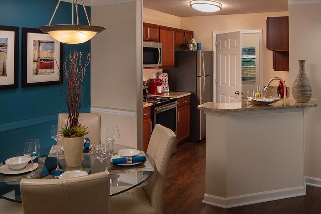 Kitchen with stainless steel appliances, bar area and wood style flooring - Wood Bridge Apartments