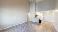 This efficiently designed one-bedroom, one-bathroom unit makes excellent use of its single-floor layout. The most striking architectural feature is the dramatically vaulted ceiling in the combined living and kitchen area, which creates a strong sense of openness and volume that far exceeds what the footprint might suggest. Light-toned, wood-style laminate flooring runs throughout the main living spaces, contributing to a clean and cohesive aesthetic.

The open-concept kitchen and living room flow seamlessly together. The kitchen is outfitted with white shaker-style cabinetry, granite-look countertops, a stainless steel sink, and stainless steel appliances including a refrigerator and dishwasher. A peninsula counter separates the kitchen from the living area, offering additional prep space. Natural light enters the living room through a window fitted with horizontal blinds, and a front entry door provides direct access.

The bedroom is a quietly proportioned room finished with soft, neutral carpeting and a window that allows natural light. A closet provides dedicated storage. The bathroom features wood-look tile flooring, a granite-topped vanity, and a full tub-shower combination with white tile surround. Throughout, the neutral color palette and clean finishes give the unit a bright, move-in-ready character.
