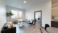 Located at 3230 Kinsrow Ave in Eugene, Oregon, this modern single-floor unit offers a thoughtfully designed open-concept layout that seamlessly connects the living, dining, and kitchen areas. Wood-look flooring runs throughout, complementing the clean white walls and contemporary aesthetic.

The living area is bright and welcoming, featuring large windows that fill the space with natural light and offer views of the surrounding Eugene landscape. The kitchen is well-appointed with two-tone cabinetry — light upper cabinets paired with dark lower units — and stainless steel appliances including a refrigerator with ice maker, range, microwave, and dishwasher. A dining area with a round table sits adjacent to the kitchen, ideal for everyday meals.

The unit includes multiple bedrooms, each with windows providing natural light and outdoor views, along with wood-look flooring. Two bathrooms serve the unit: one featuring a full tub-shower combination with a clean white surround, and a second with a vanity and large mirror, both finished with dark cabinetry and wood-look tile flooring.

The floor plan, visible in the 3D model, reveals a well-organized layout with private bedroom corridors, ample shared living space, and multiple bathroom access points, making this unit functional for shared or individual occupancy.