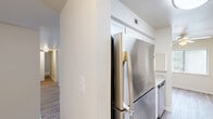 Located at 3006 Hickory Woods Dr NE in Roanoke, Virginia, this single-floor residence offers a thoughtfully designed layout comprising one bedroom, two bathrooms, a combined kitchen and living room, a utility room, and a closet. The galley-style kitchen is a standout feature, showcasing white shaker cabinetry, light stone-look countertops, and stainless steel appliances including a French door refrigerator, electric range with over-the-range microwave, and dishwasher. Light wood-look flooring runs throughout the main living areas, lending a clean, cohesive aesthetic. The living room is bright and open, with a pass-through window connecting to the kitchen and a sliding glass door that opens onto a private deck with lush tree views, filling the space with natural light. The bedroom is carpeted for comfort, features a ceiling fan with light, and includes a window with outdoor views. Both bathrooms are finished with white tub-shower combinations, with one offering a white vanity and wood-look flooring. Neutral, warm-toned walls throughout contribute to a light and airy ambiance, making this a comfortable and functional residence in a convenient Roanoke location.