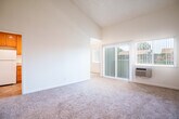 Located at 2511 Grove Way in Castro Valley, California, this single-story, 4-bedroom, 1-bathroom home offers a practical and comfortable layout with several notable architectural features. The living area immediately impresses with its dramatic vaulted ceilings, which create a strong sense of openness and volume. Soft wall-to-wall carpeting runs throughout the living and bedroom spaces, lending warmth underfoot. Natural light filters in through vertical-blind-covered windows and a sliding glass door, brightening the main living area. The kitchen is well-appointed with warm honey-toned cabinetry, granite countertops, white appliances including a range, dishwasher, refrigerator, and microwave, and durable tile flooring. A window at the end of the kitchen brings in additional natural light. The four bedrooms are carpeted and feature neutral walls, offering versatile spaces for various uses. The primary bedroom is generously sized, providing ample room for furnishings. The full bathroom includes a single-sink vanity with warm wood cabinetry and a granite countertop, tile flooring, and a frosted glass shower door. A hallway and closet round out the interior, keeping the layout organized and efficient throughout.