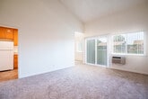 Located at 2511 Grove Way in Castro Valley, California, this single-story, 4-bedroom, 1-bathroom home offers a practical and comfortable layout with several notable architectural features. The living area immediately impresses with its dramatic vaulted ceilings, which create a strong sense of openness and volume. Soft wall-to-wall carpeting runs throughout the living and bedroom spaces, lending warmth underfoot. Natural light filters in through vertical-blind-covered windows and a sliding glass door, brightening the main living area. The kitchen is well-appointed with warm honey-toned cabinetry, granite countertops, white appliances including a range, dishwasher, refrigerator, and microwave, and durable tile flooring. A window at the end of the kitchen brings in additional natural light. The four bedrooms are carpeted and feature neutral walls, offering versatile spaces for various uses. The primary bedroom is generously sized, providing ample room for furnishings. The full bathroom includes a single-sink vanity with warm wood cabinetry and a granite countertop, tile flooring, and a frosted glass shower door. A hallway and closet round out the interior, keeping the layout organized and efficient throughout.